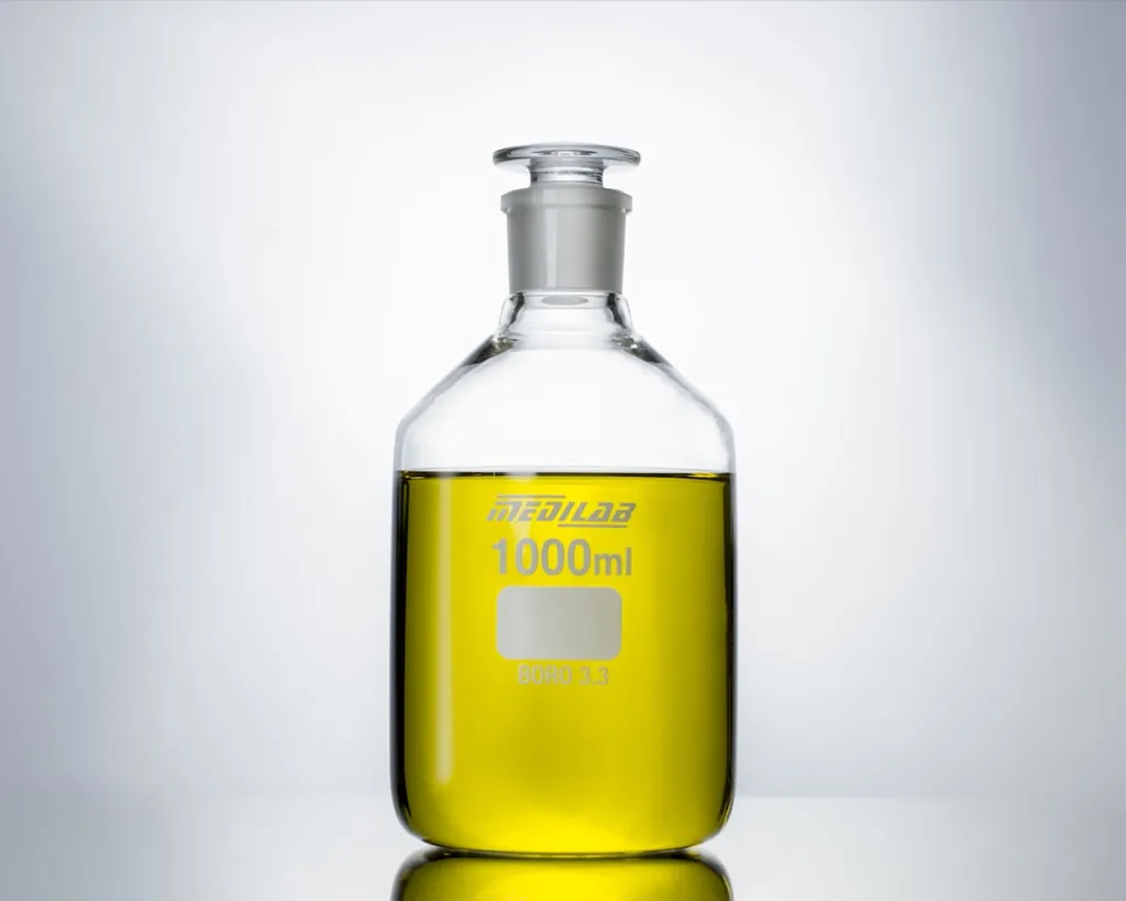 Borosilicate laboratory bottle labeled 1000 ml, partially filled with a clear yellow liquid, photographed against a soft white background.